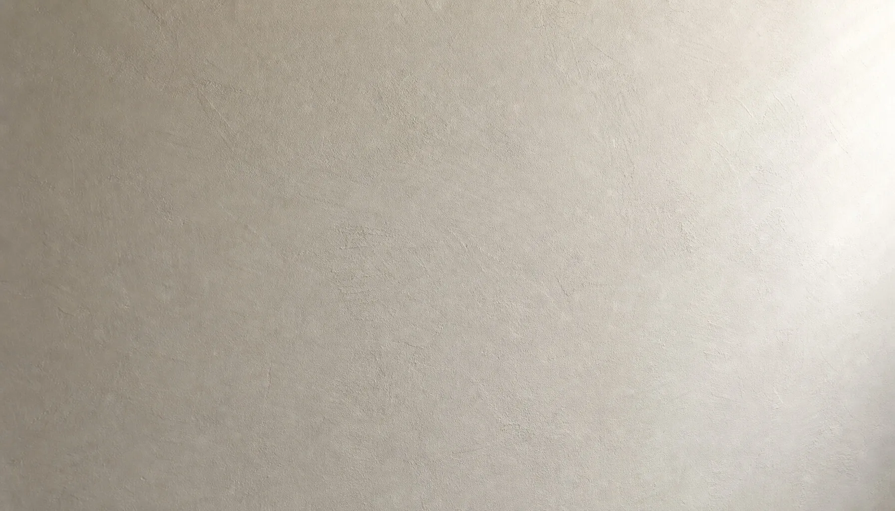 Glatt verputzte, matte Wand in warmem Off-White mit streifendem Tageslicht.